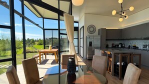A modern kitchen with a built-in refrigerator, a dining area with a glass table, and a view of the outdoors. - Panoramic by Carmelodays (Carmelo)