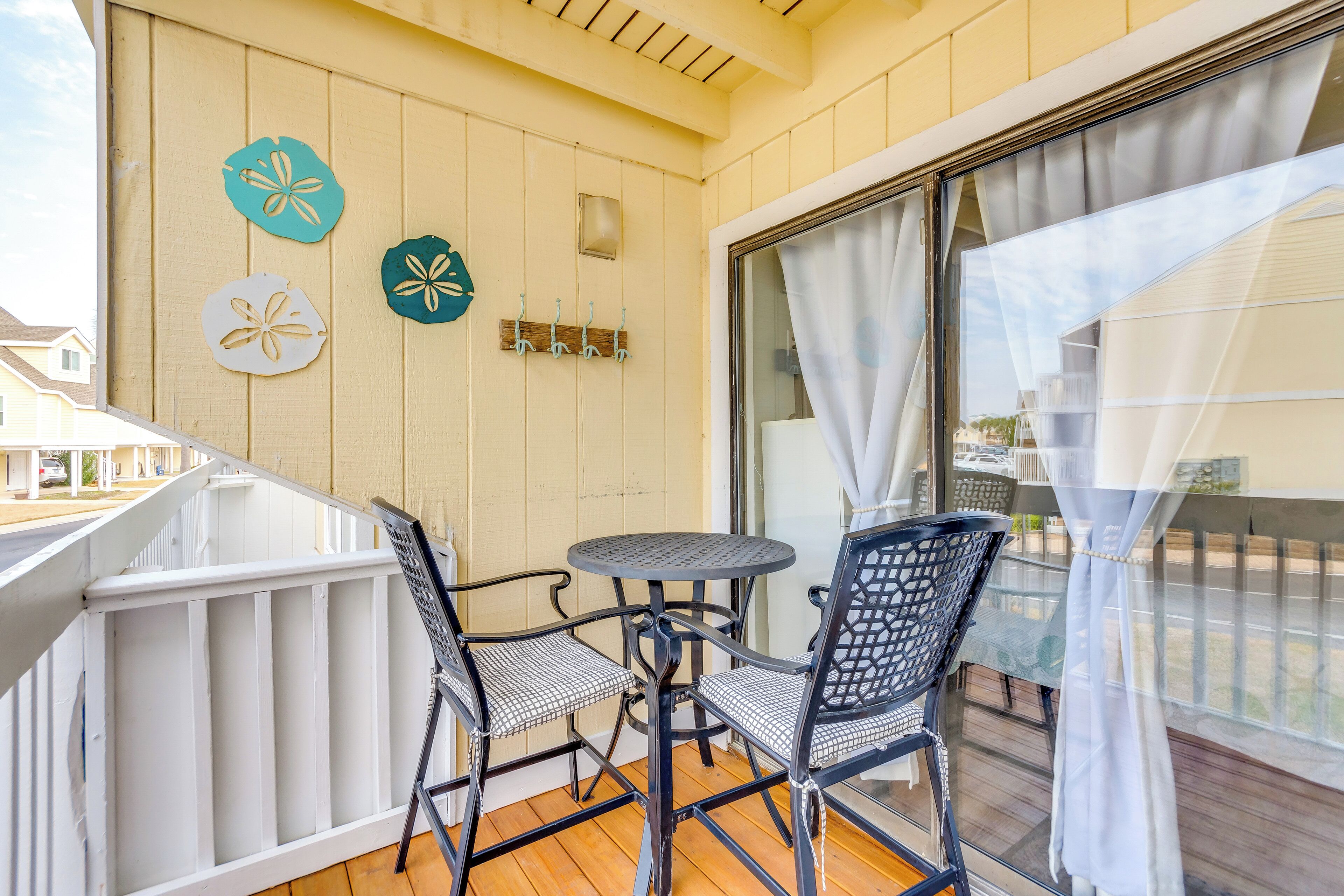 Un balcon avec une table et deux chaises, une balustrade blanche et des éléments décoratifs sur le mur.