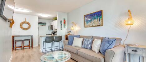 Ein modernes Wohnzimmer mit einer Couch, einem Glastisch und einem Essbereich mit Stühlen.