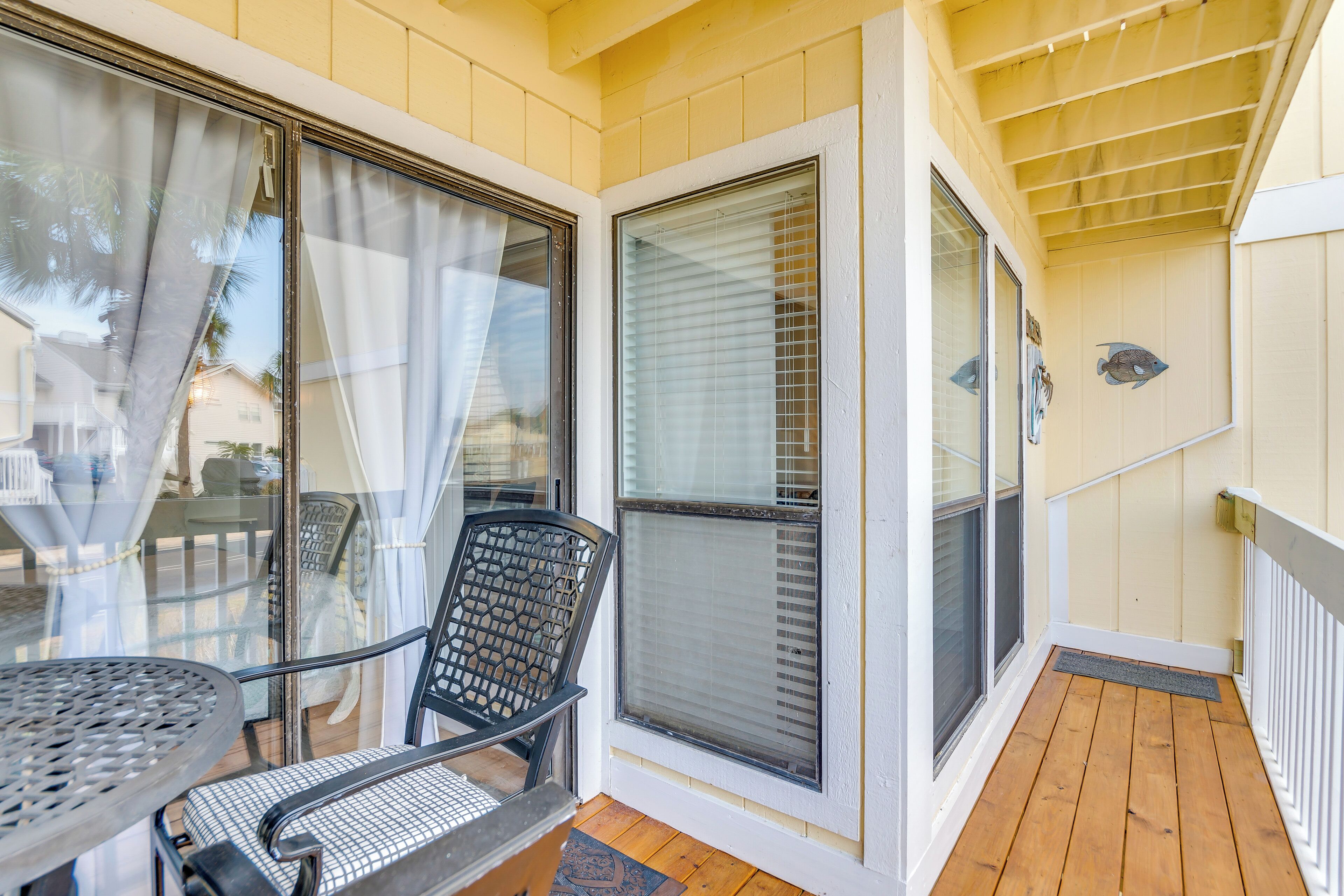 A covered porch with a table and chairs, a sliding glass door, and a wooden deck.