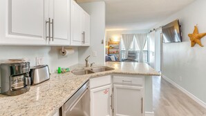 A kitchen with white cabinets, a granite countertop, a coffee maker, and a toaster. - Walk to Beach: Resort Retreat w/ Balcony in Destin (Destin)