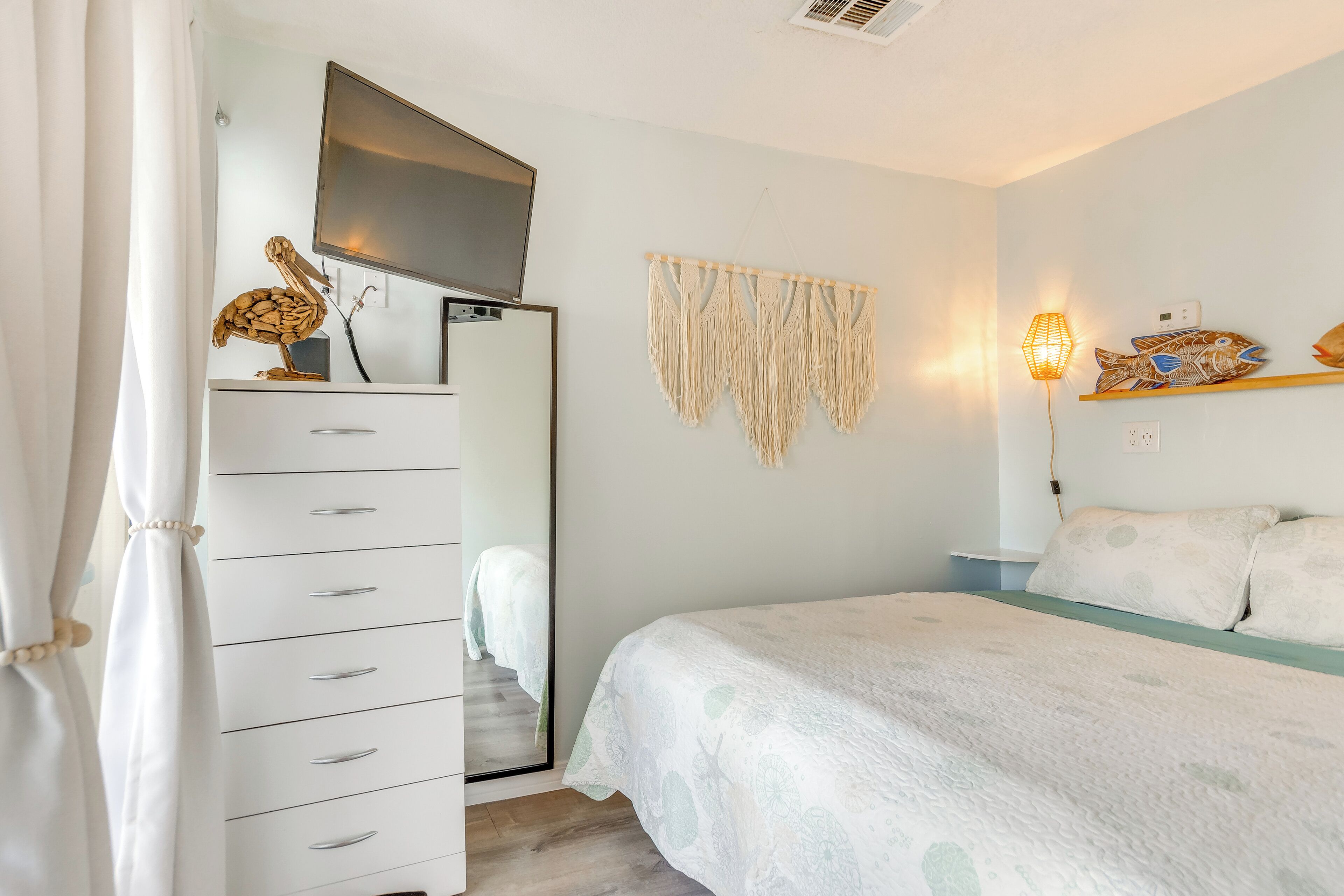 Un dormitorio con cama, cómoda, espejo y decoración en la pared.