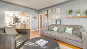 Ein modernes Wohnzimmer mit einem grauen Sofa, einem schwarzen Couchtisch und einem Essbereich, der durch einen Bogen sichtbar ist.
