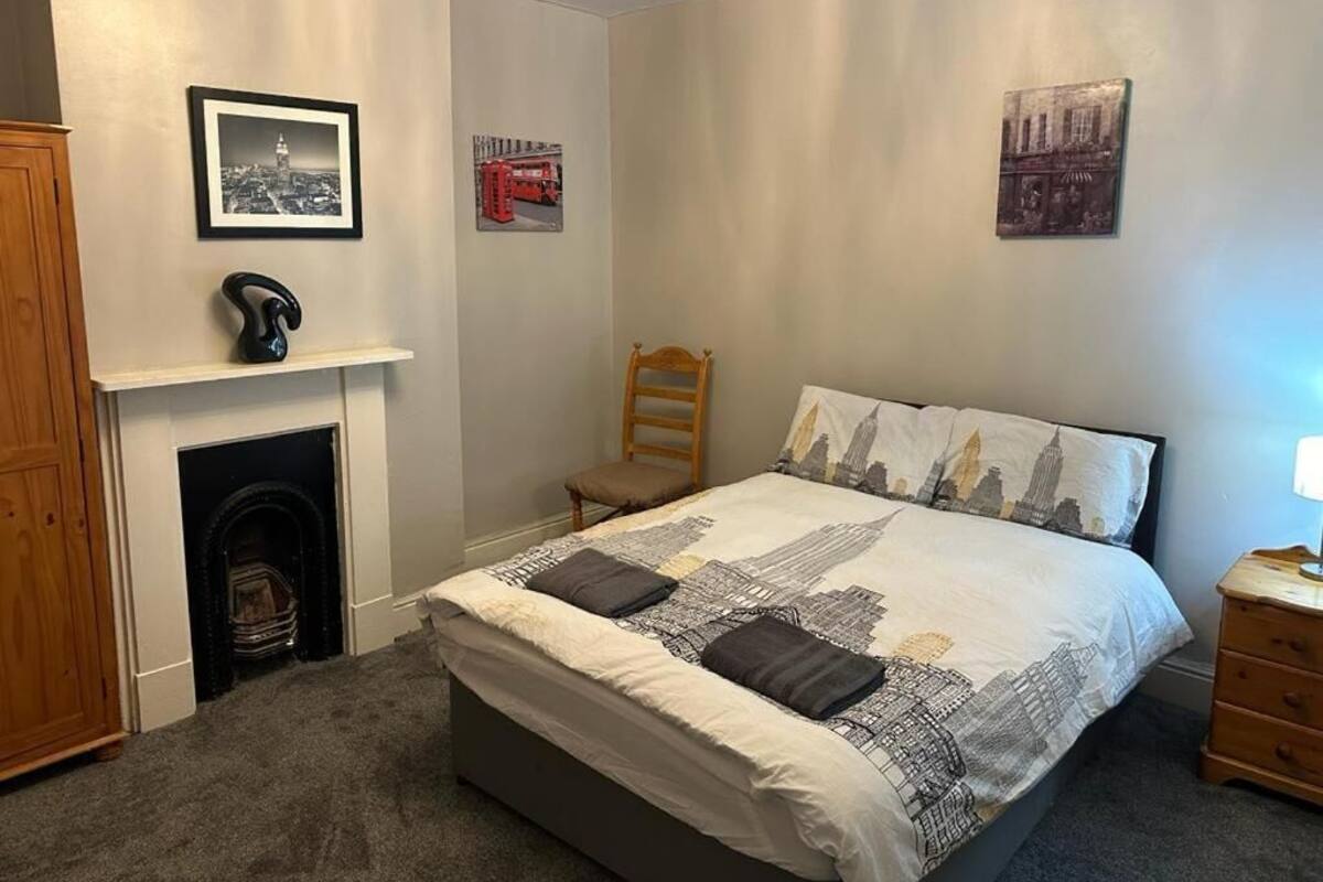 Quarto com cama, cadeira, lareira e obras de arte nas paredes.