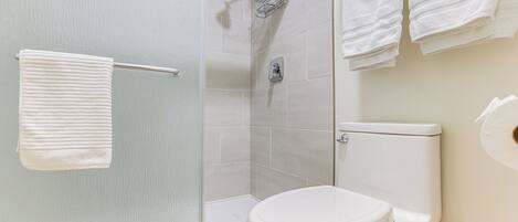 Un baño con inodoro, ducha y toallero.