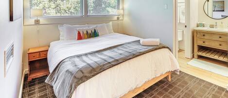 A bedroom with a bed, bedside table, and a window with blinds.