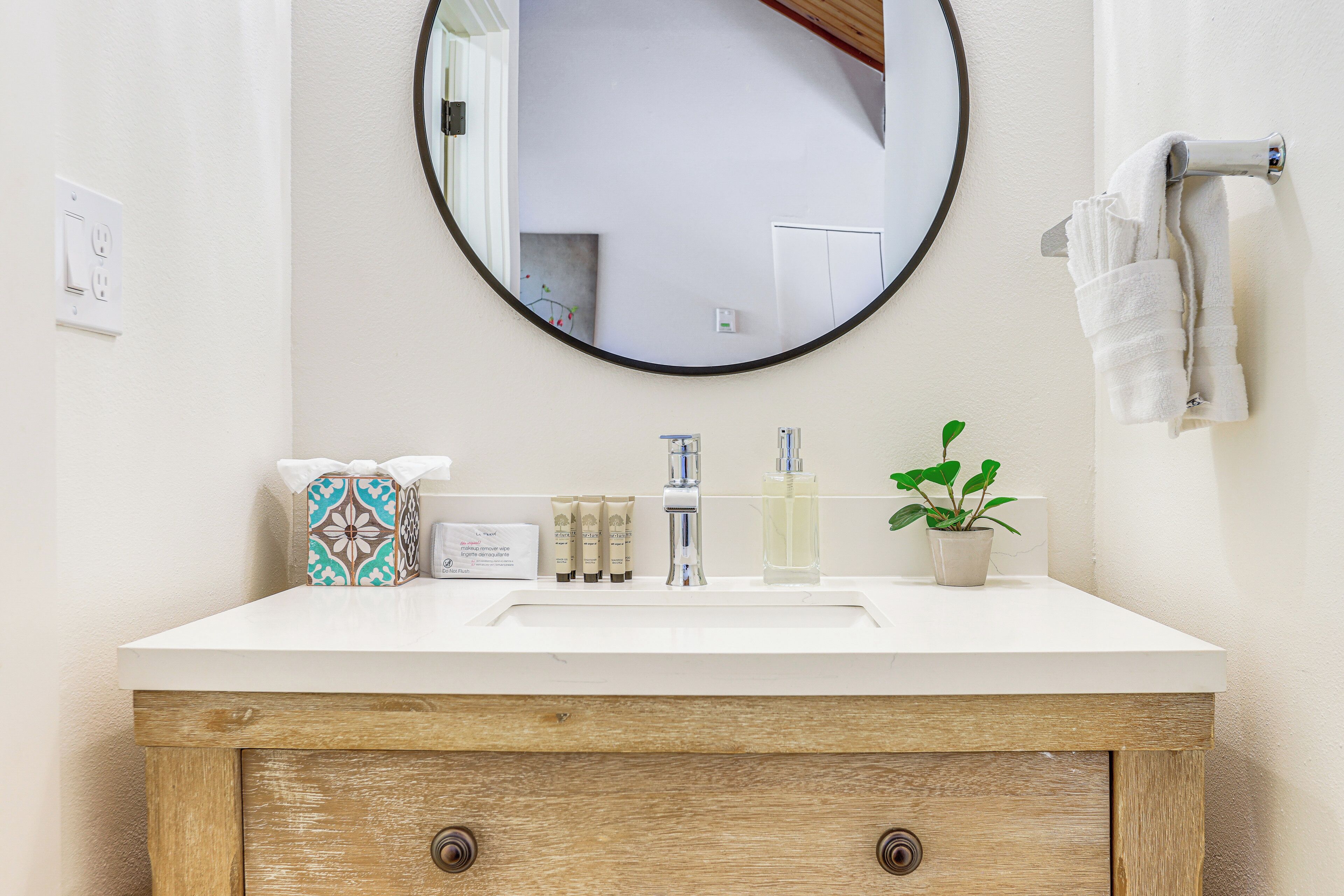 A bathroom with a white sink, wooden cabinet, and a mirror.