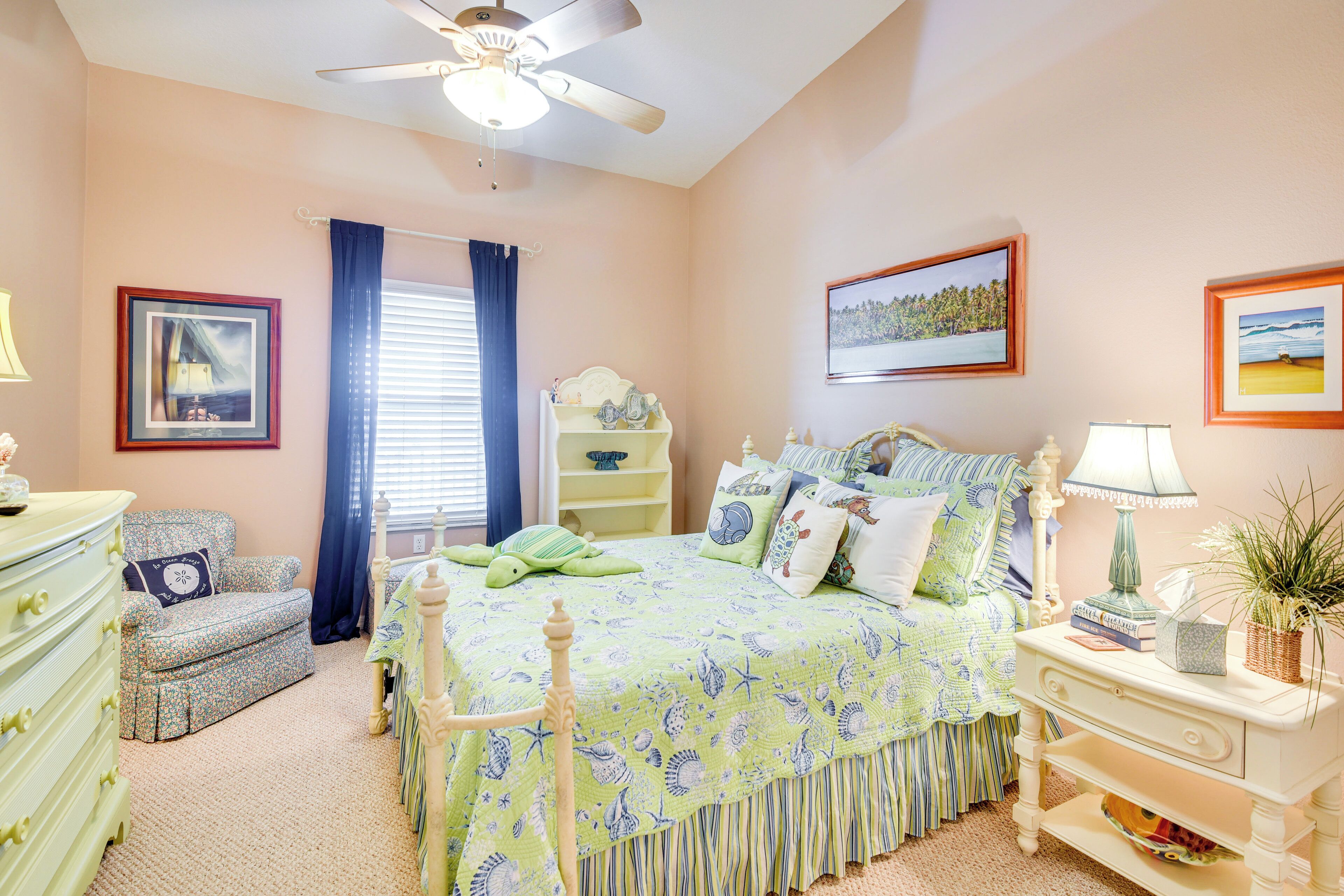 A bedroom with a bed, dresser, nightstand, and a ceiling fan.