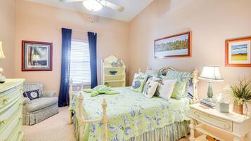 A bedroom with a bed, dresser, nightstand, and a ceiling fan.