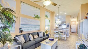 A spacious living room with a gray sofa, a coffee table, and a view of the ocean through large windows. - Community Pool: Coastal Escape in Flagler Beach (Flagler Beach)