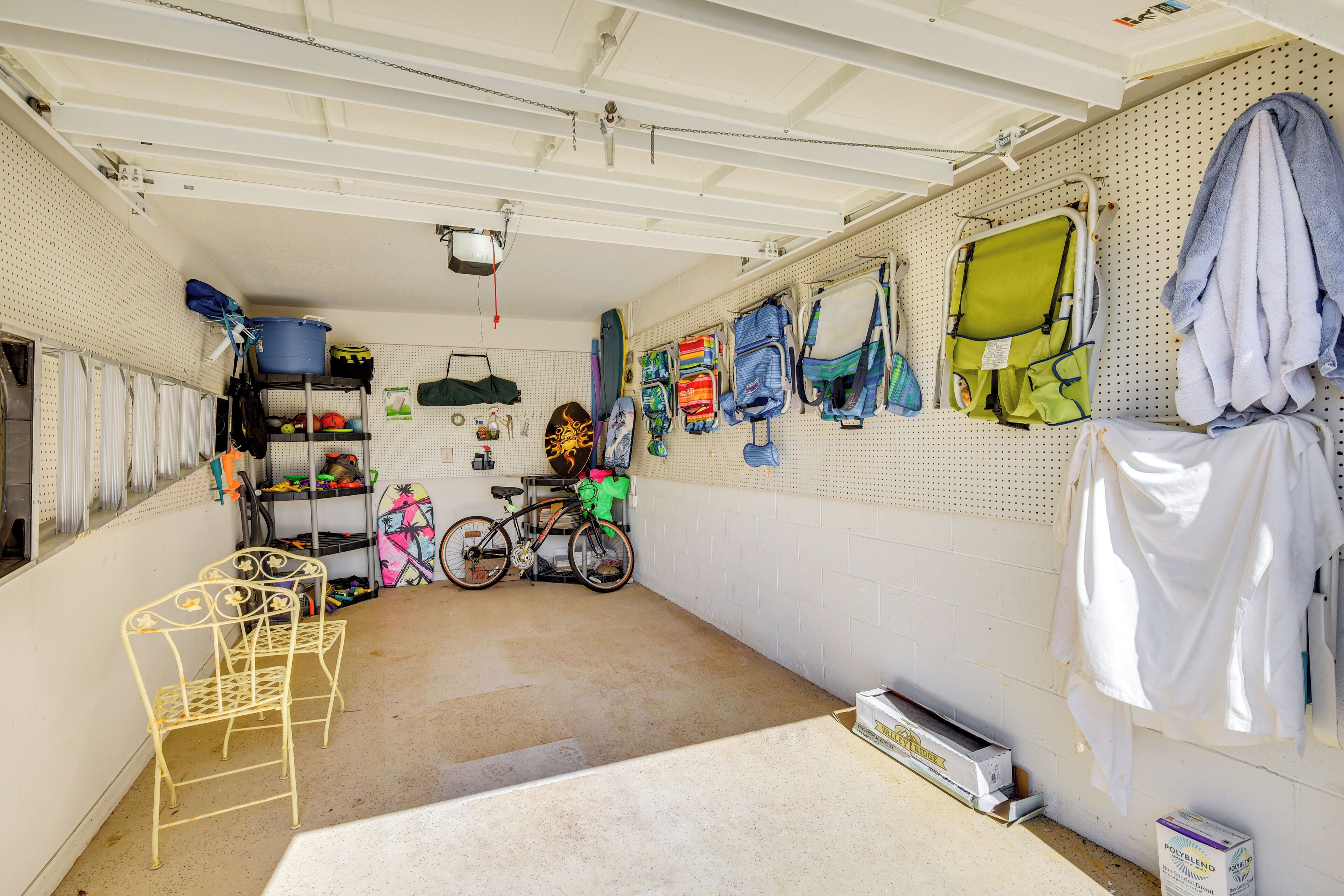 Un garage contenant des vélos, une chaise en métal, ainsi que divers sacs et cartons.