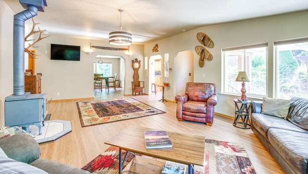 A spacious living room with a fireplace, leather armchair, and a large window providing a view of the outdoors. - 11 Acres of Adventure! Woodsy Mead Stay w/ Trails (Mead)