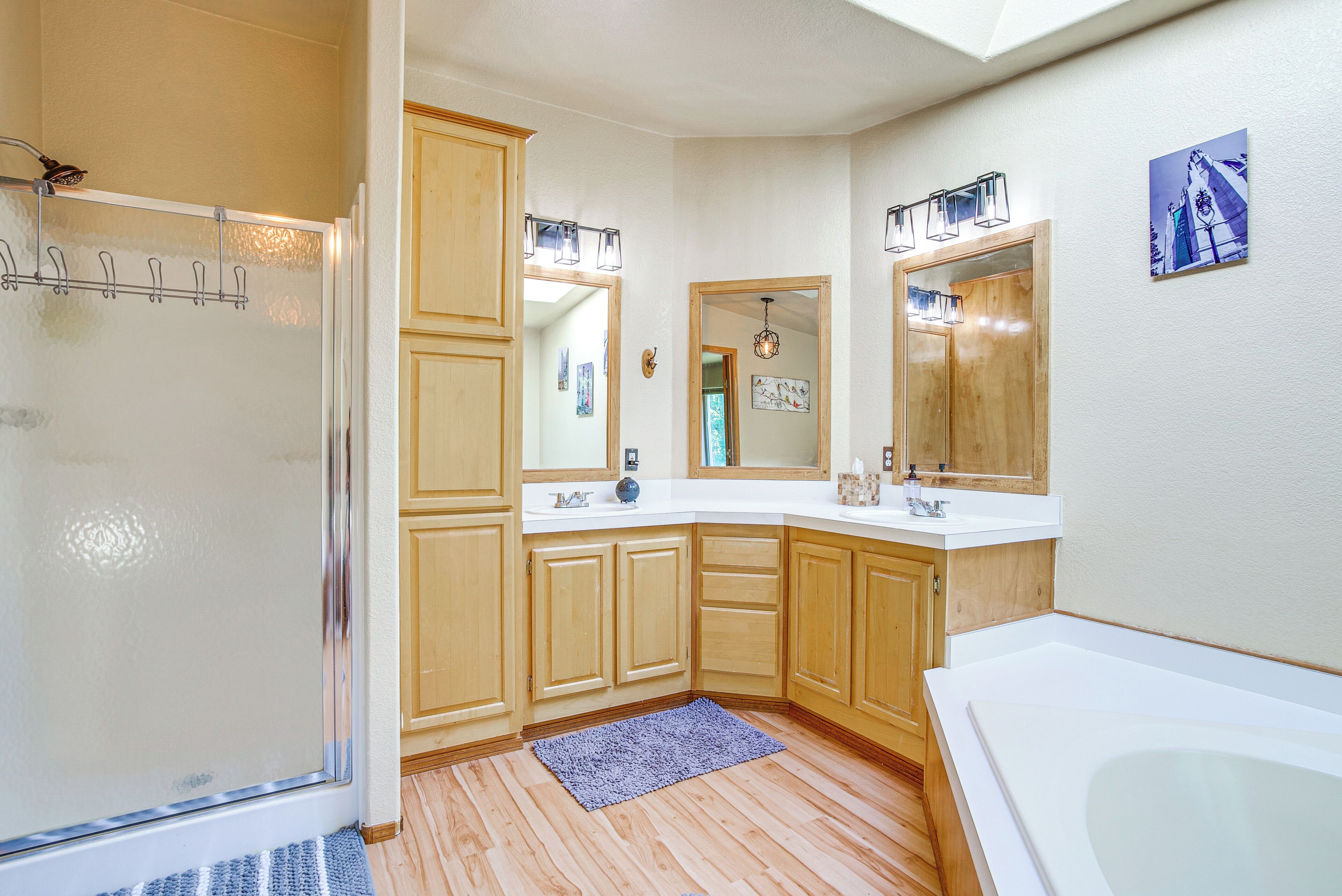 A bathroom with wooden cabinets, a shower, a bathtub, and a vanity with a mirror.