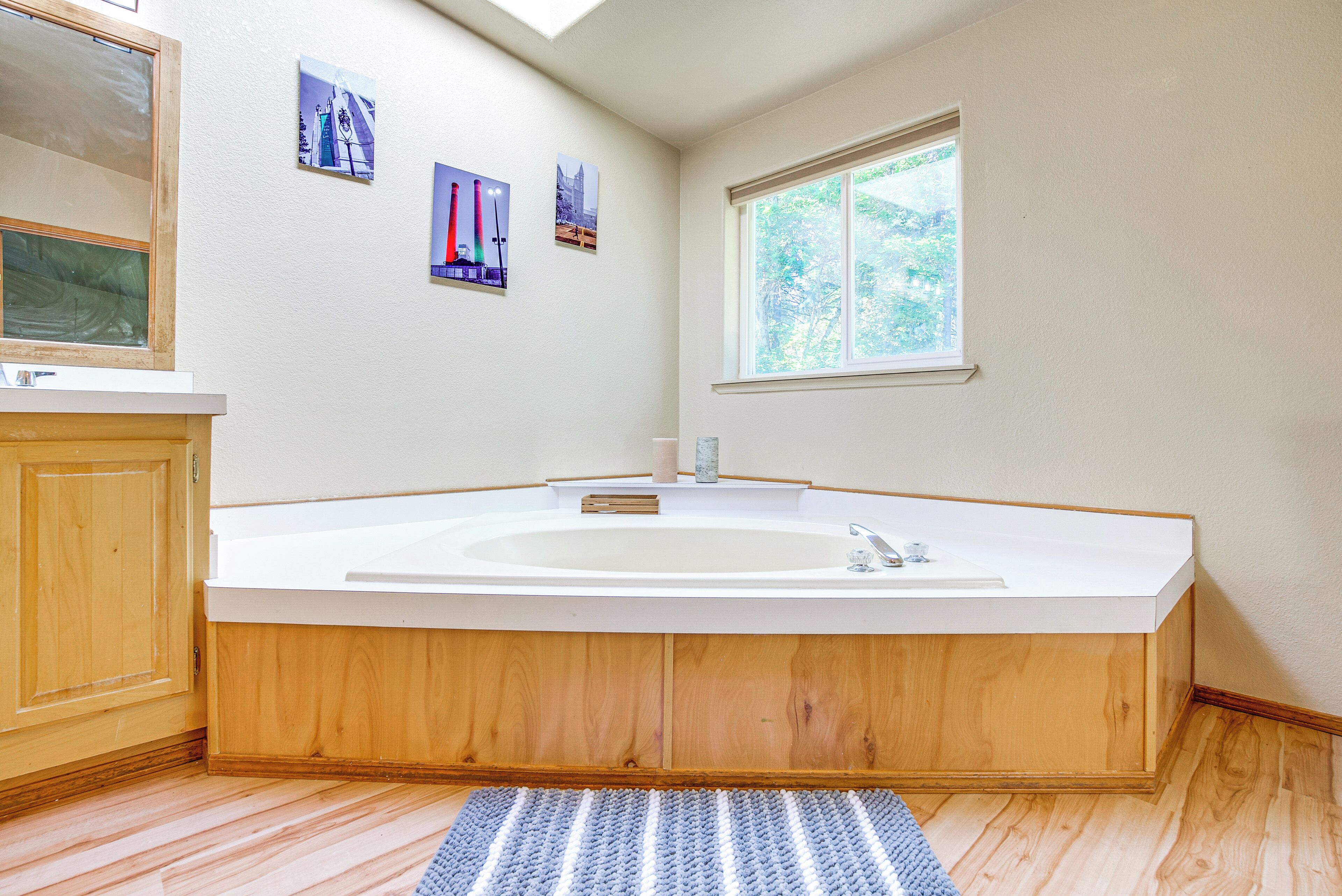 A modern bathroom with a freestanding bathtub, wooden cabinetry, and a window providing natural light.