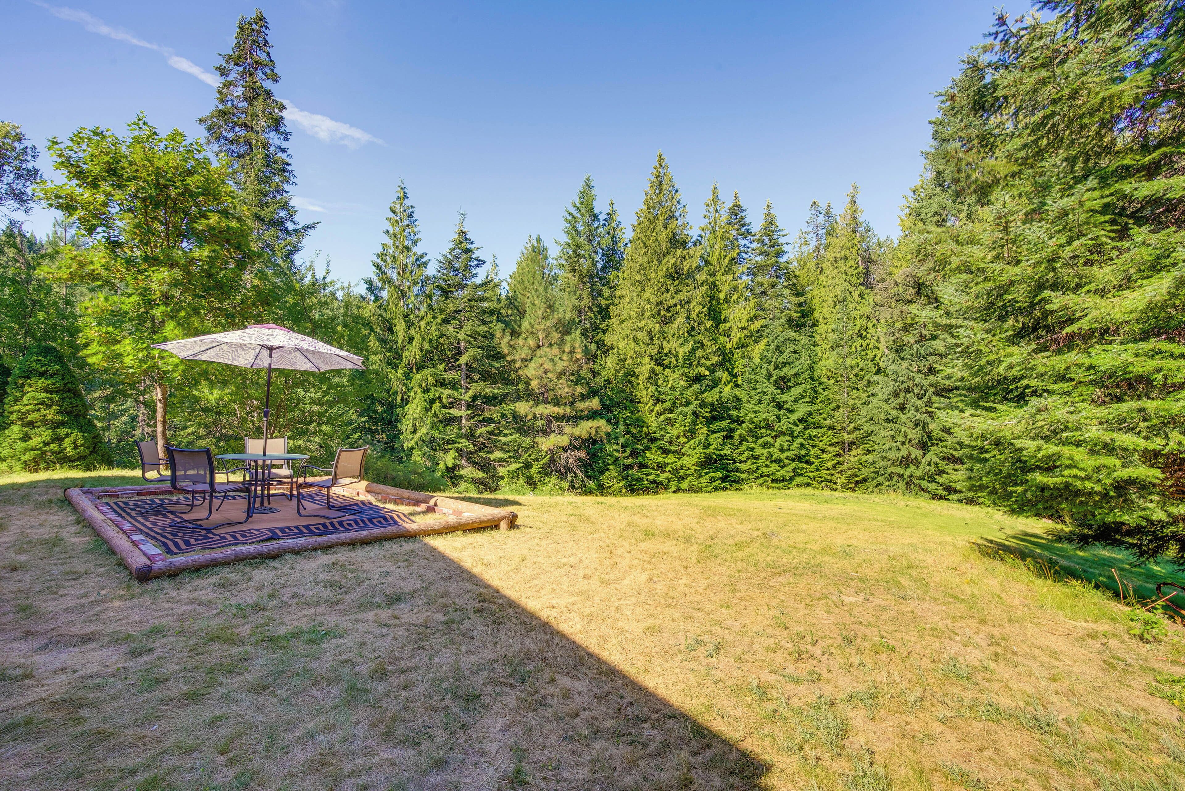 A patio area with a table and chairs, surrounded by a lush green forest.