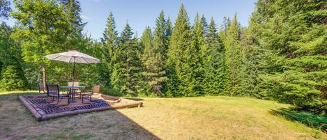A patio area with a table and chairs, surrounded by a lush green forest.