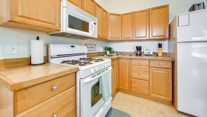 A kitchen with wooden cabinets, a white stove, a microwave, and a refrigerator. - Kenai River Views & Access: Soldotna Apartment! (Soldotna)