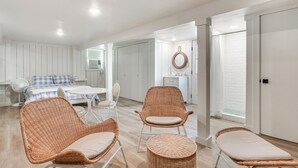 A modern, well-lit room with a bed, two wicker chairs, a small table, and a fan. - Walk to Lake Texoma: Kingston Retreat w/ Deck! (Kingston)