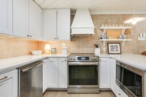 A kitchen with white cabinets, a stainless steel oven, a microwave, and a patterned backsplash. - Walk to Lake Texoma: Kingston Retreat w/ Deck! (Kingston)