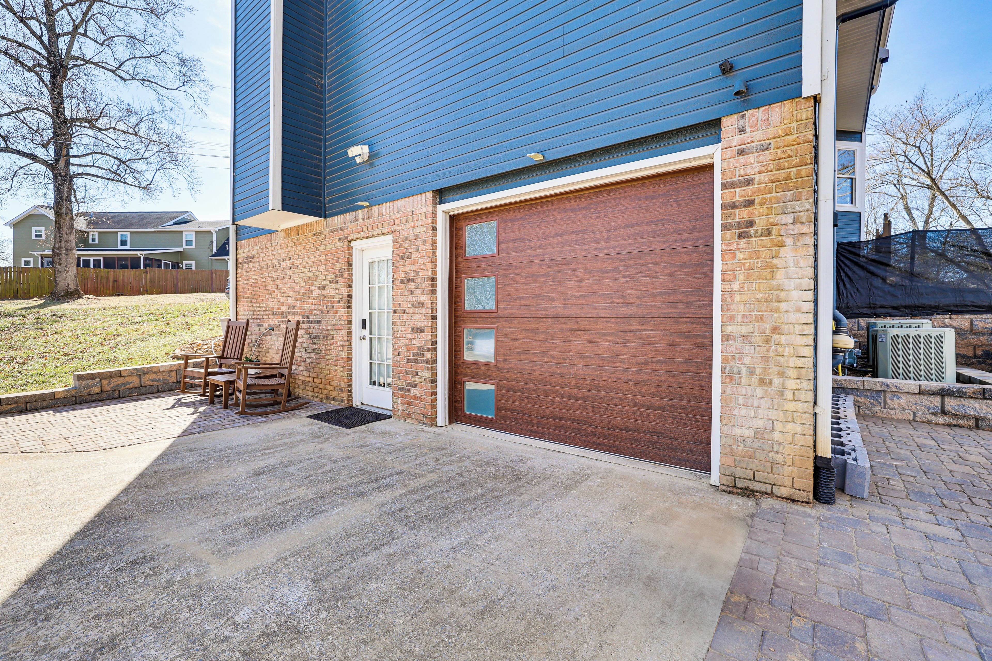 A garage with a brown door, a brick wall, and a blue siding exterior.