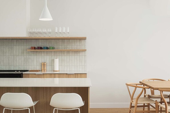 A modern kitchen with a white countertop, wooden cabinets, and a dining area with a wooden table and chairs.