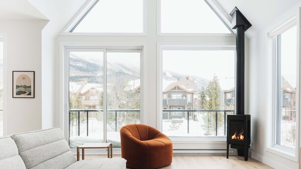 Una sala moderna con un amplio ventanal, una chimenea y un sillón acogedor.