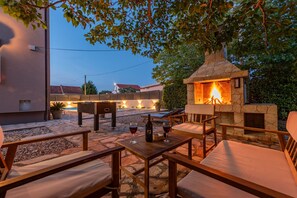 Eine Terrasse im Freien mit Steinböden, Holzmöbeln und einem Kamin aus Stein.