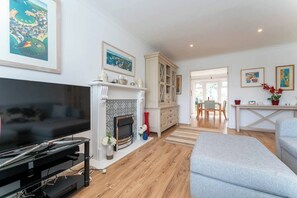 A modern living room with a fireplace, a television, and a dining area with a table and chairs. - New perfect 3 bed house with garden and PARKING! (Brighton and Hove)