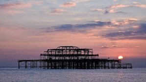 Una estructura de muelle se adentra en el agua al atardecer.