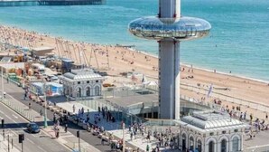 Zona costera con una torre destacada, playa y un muelle al fondo.