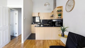 A modern kitchen with wooden cabinets, a black countertop, and a wall-mounted clock.