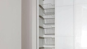 A white closet with wire baskets on shelves.