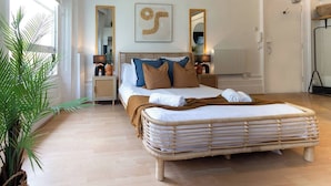 Ein geräumiges Schlafzimmer mit einem großen Bett, einem Nachttisch, einem Spiegel und einer Zimmerpflanze.