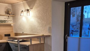 A compact kitchen with a wooden countertop, a built-in oven, and a dining area with a round table and two chairs.