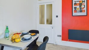 Et spiseområde med et bord dækket til to personer, en vandflaske, en skål jordbær og en croissant.