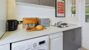 Et moderne køkken med stålemfangere, en skærebræt med croissanter og et indrammet kunstværk på væggen.