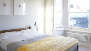 A bedroom with a bed, a window, a radiator, and wall-mounted pictures. - London 2-bed Apartment in Herbert Road (London)