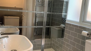 Un baño con cabina de ducha de vidrio, un lavamanos blanco y un inodoro.