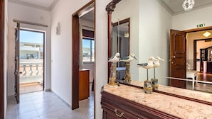 Pasillo de hotel con mostrador de mármol, puertas de madera y un espejo grande que refleja vistas a un balcón.