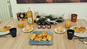 Mesa de café da manhã com croissants, suco e uma garrafa de drink.