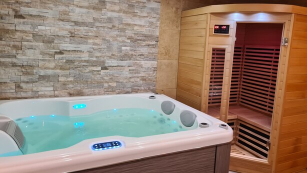 Um quarto de spa com parede de pedra, banheira de hidromassagem e sauna de madeira.