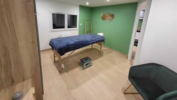 A bedroom with a bed, a stool, a ladder, and a green wall.