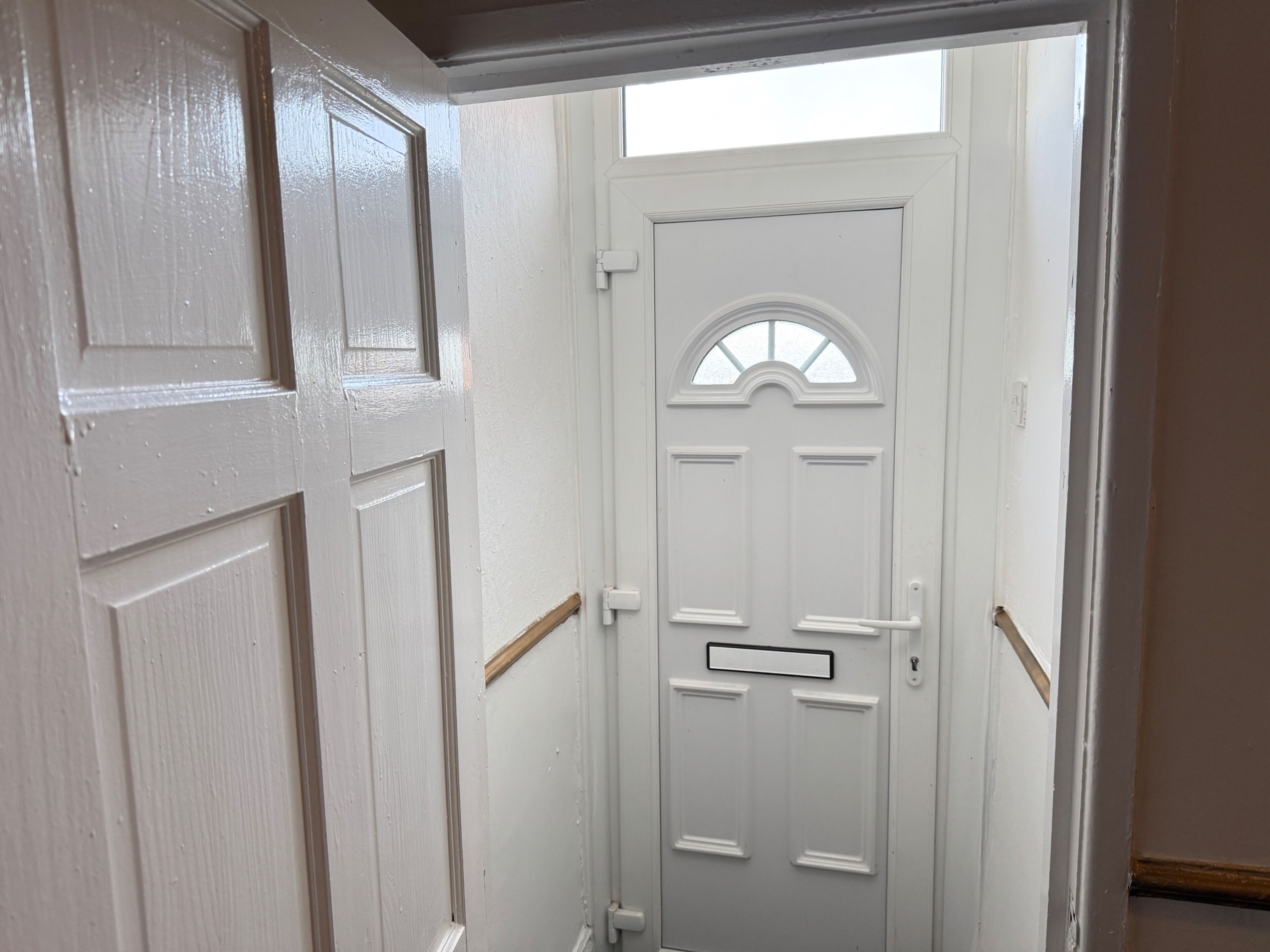 A white door with a small window and a mail slot.