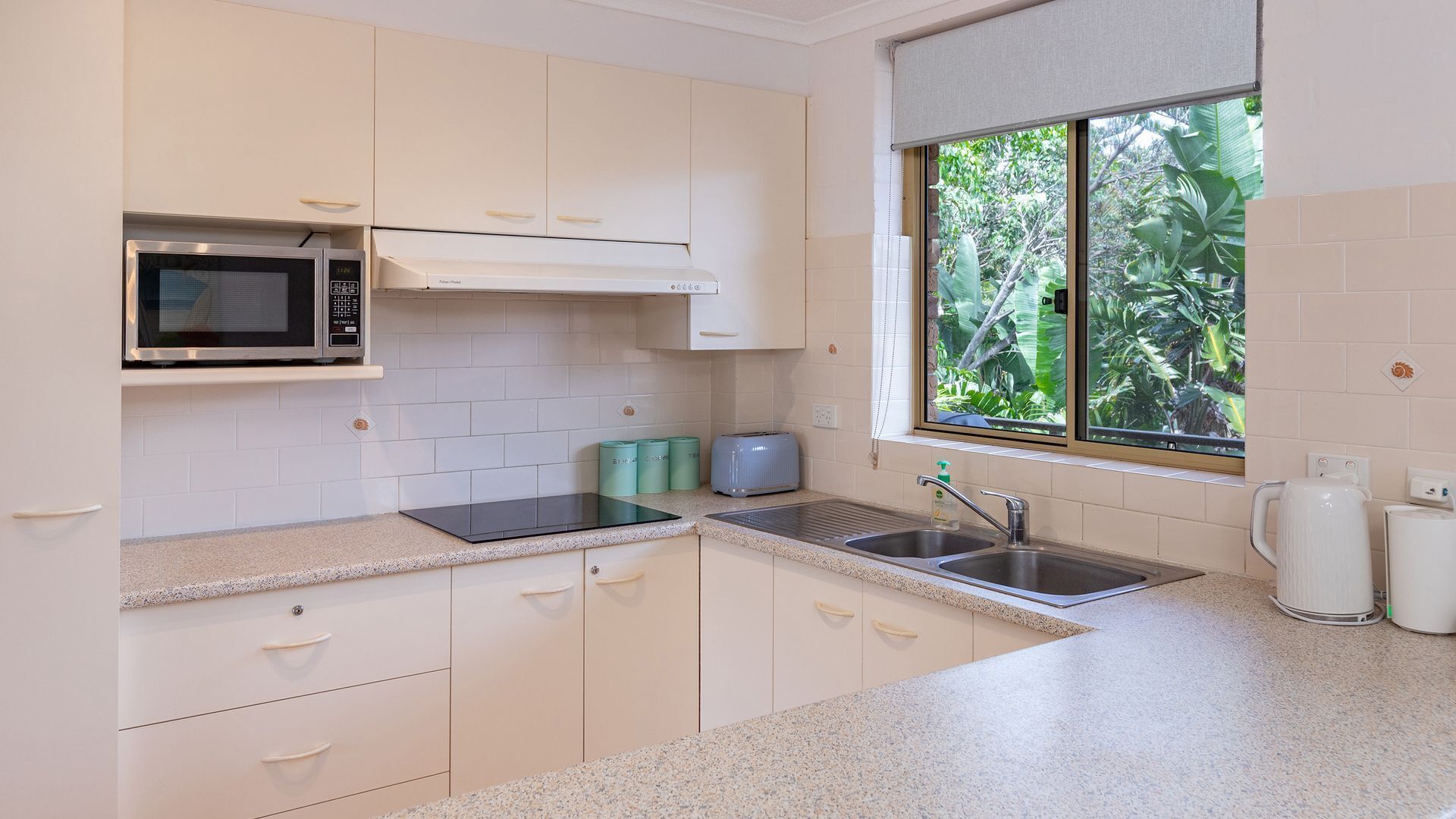 A modern kitchen with white cabinets, a microwave, a toaster, and a sink.