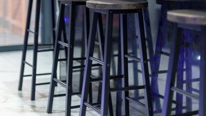 Una cocina moderna con un amplio ventanal, un lavamanos y tres taburetes.