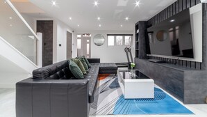 Una sala de estar moderna con un sofá de cuero negro, un televisor de pantalla plana grande y un diseño minimalista.
