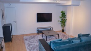 Una sala de estar moderna con televisor de pantalla plana, un sofá, una mesa de centro y una planta en maceta.