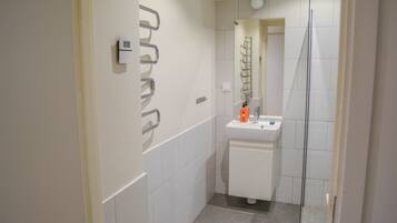 A modern bathroom with a white sink, mirror, and shower.
