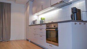 Una cocina moderna con electrodomésticos de acero inoxidable, armarios blancos y piso de madera.