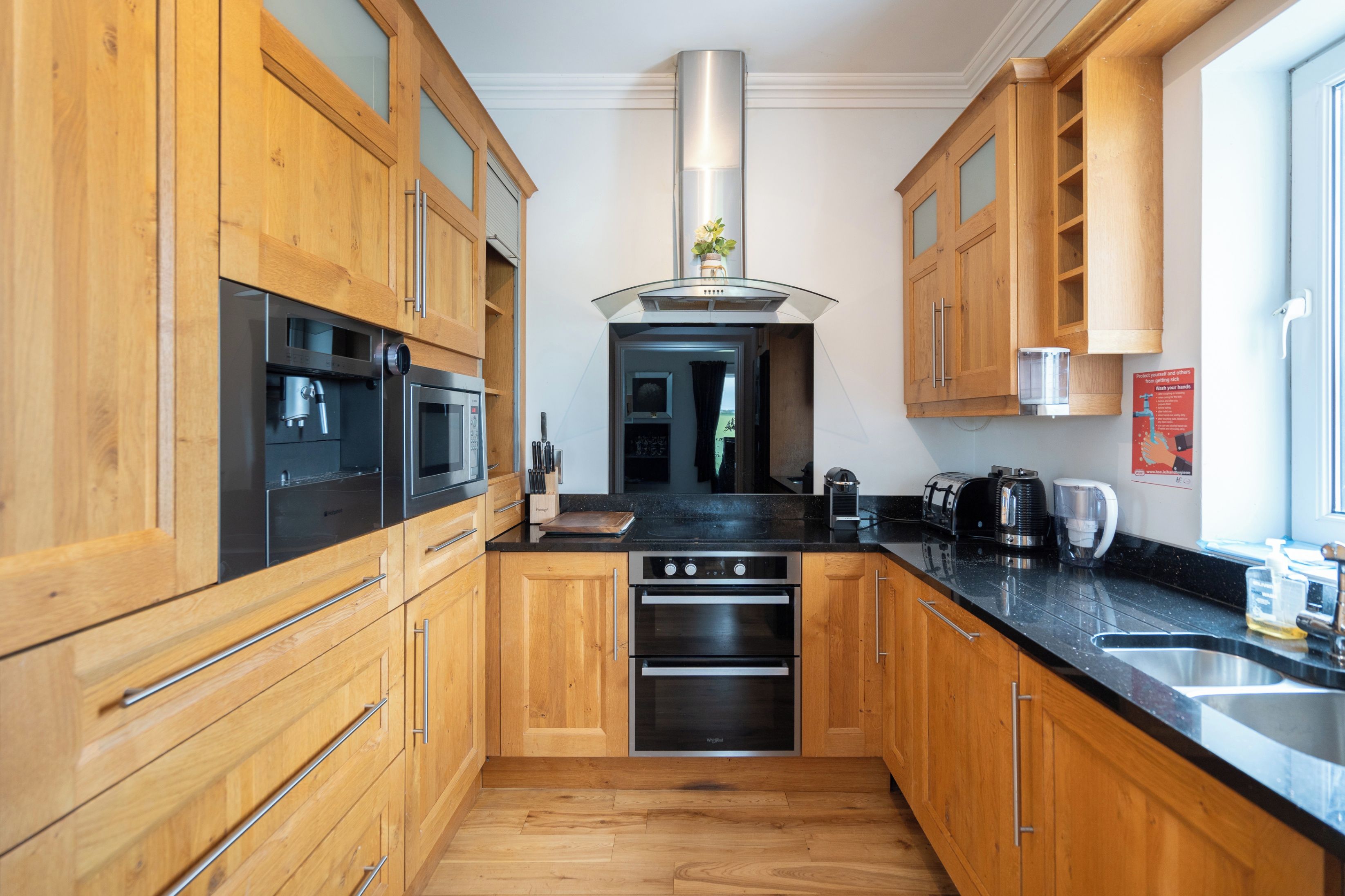 A modern kitchen with wooden cabinets, stainless steel appliances, and a black countertop.